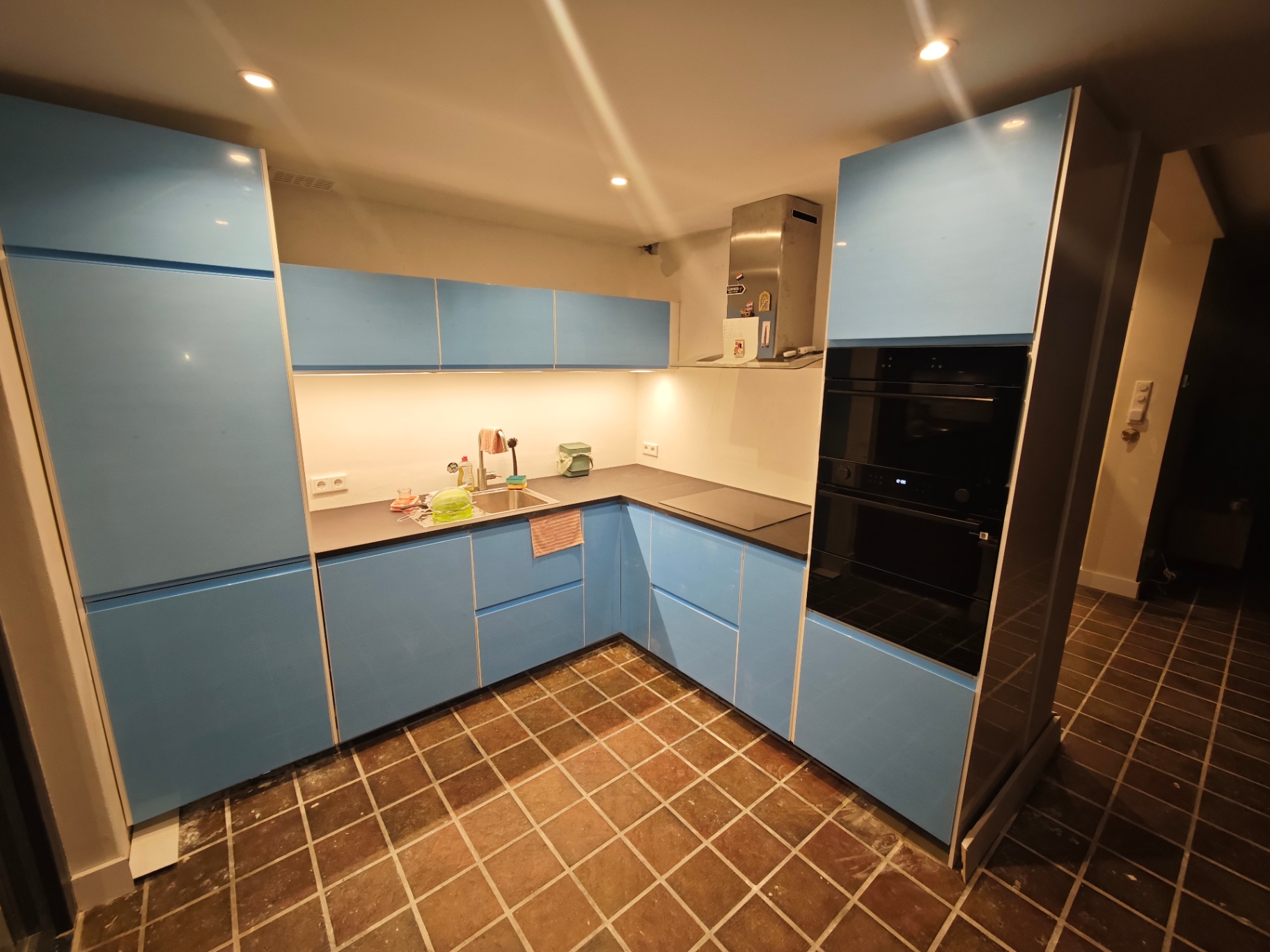 Keuken met blauwe kastfronten en een tegelvloer